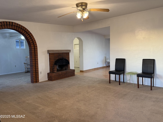 4910 N Gold Ave, Tucson, AZ 85705 - unfurnished living room featuring ceiling fan, a brick fireplace, arched walkways, and carpet flooring