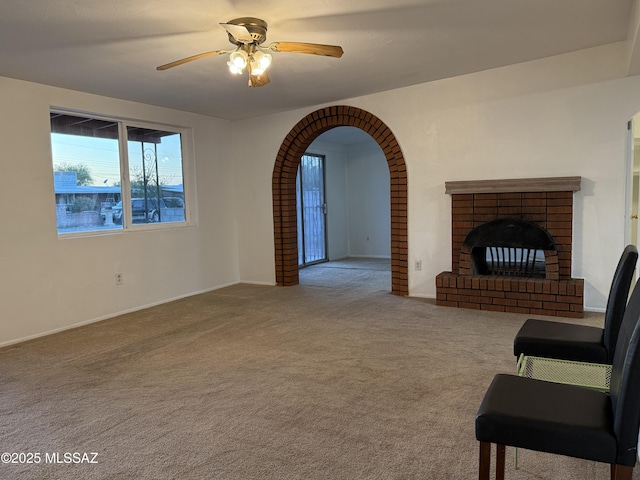 4910 N Gold Ave, Tucson, AZ 85705 - unfurnished living room with carpet, ceiling fan, a fireplace, baseboards, and arched walkways