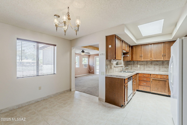 140 W Calle Melendrez, Green Valley, AZ 85614 - kitchen with freestanding refrigerator, dishwashing machine, light countertops, a chandelier, and brown cabinetry