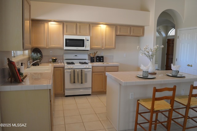 1645 E Ganymede Dr, Tucson, AZ 85737 - kitchen featuring white appliances, tile counters, a sink, arched walkways, and light tile patterned floors