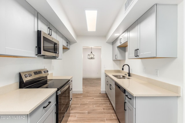 1200 S Alpine Cir, Green Valley, AZ 85614 - kitchen featuring stainless steel appliances, a sink, wood tiled floors, baseboards, and light countertops