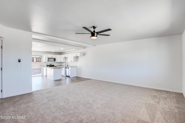 9570 E Sellarole Rd, Tucson, AZ 85730 - unfurnished living room with light colored carpet, a ceiling fan, baseboards, recessed lighting, and a sink