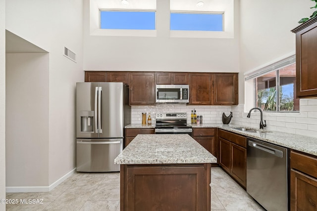 2742 S Via Del Bac, Green Valley, AZ 85622 - kitchen featuring appliances with stainless steel finishes, a towering ceiling, a sink, baseboards, and tasteful backsplash