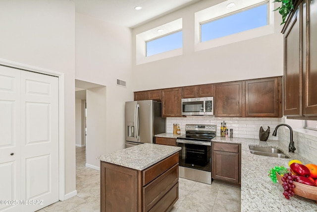 2742 S Via Del Bac, Green Valley, AZ 85622 - kitchen with stainless steel appliances, a sink, a towering ceiling, decorative backsplash, and light stone counters