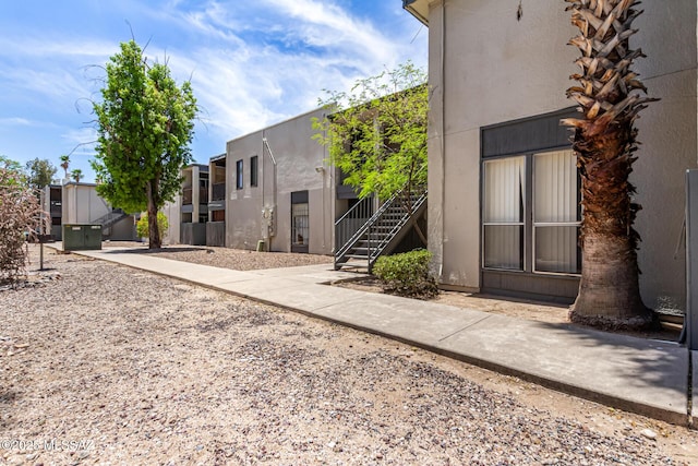 back of property with stucco siding and stairs