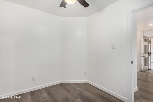 spare room with dark wood finished floors, a ceiling fan, and baseboards