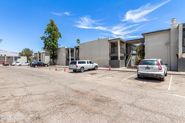 view of property with uncovered parking, stairs, and a residential view