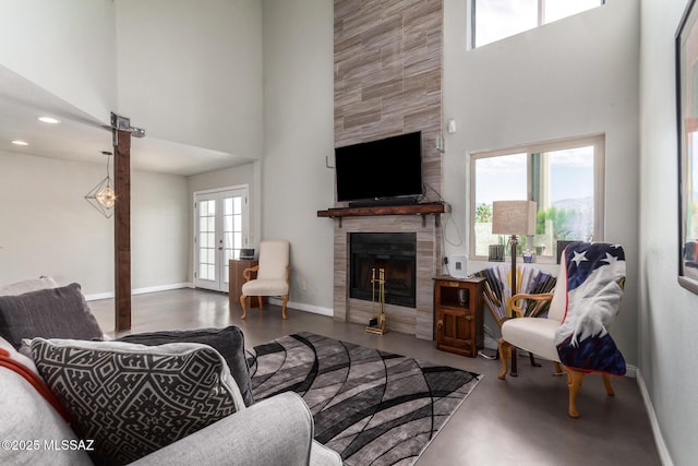 living room with a high ceiling, baseboards, a fireplace, french doors, and recessed lighting
