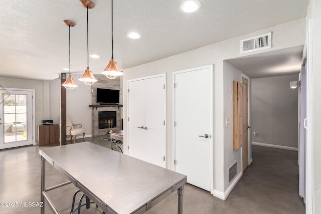 kitchen featuring finished concrete floors, baseboards, a fireplace, recessed lighting, and a textured ceiling