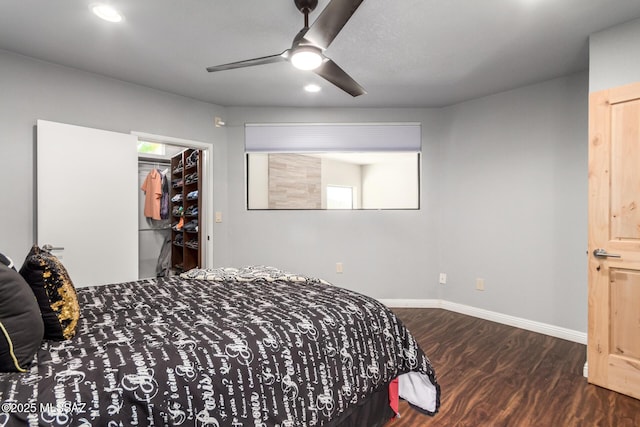 bedroom featuring wood finished floors, recessed lighting, a walk in closet, baseboards, and ceiling fan