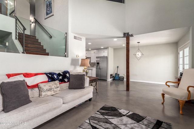 living room with concrete floors, stairway, a towering ceiling, baseboards, and recessed lighting