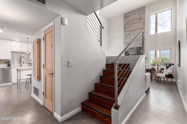 staircase featuring concrete floors, a textured wall, and baseboards