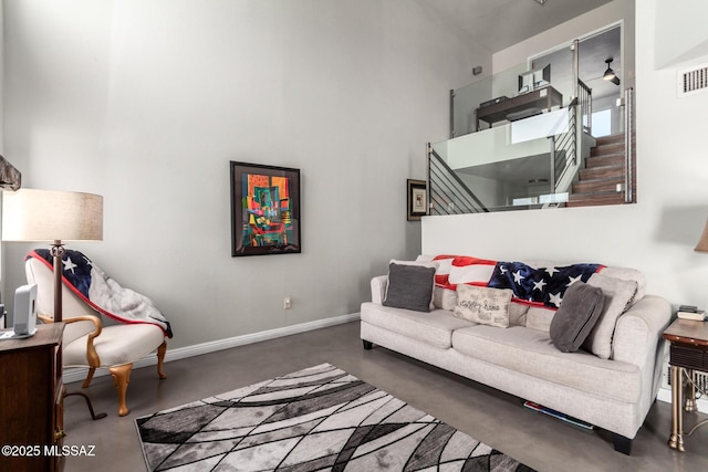 carpeted living area with a towering ceiling and baseboards