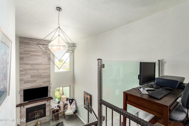 office area featuring a tiled fireplace and a chandelier