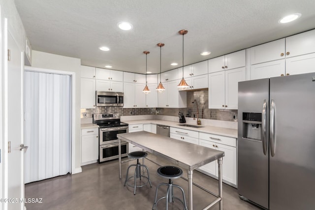 kitchen with appliances with stainless steel finishes, a sink, finished concrete floors, tasteful backsplash, and white cabinets