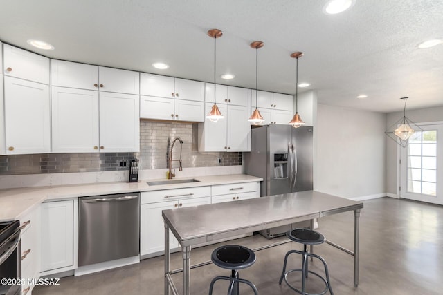 kitchen with appliances with stainless steel finishes, a sink, decorative backsplash, a breakfast bar area, and white cabinetry