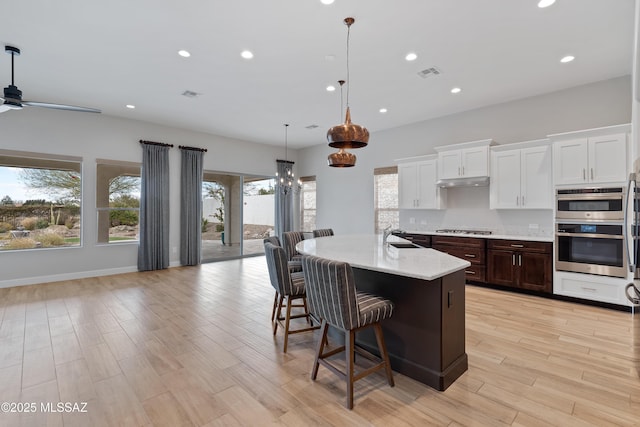 31566 S Misty Basin Rd, Oracle, AZ 85623 - kitchen with stainless steel gas cooktop, recessed lighting, light wood-type flooring, white cabinets, and a sink