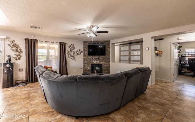 13570 E Hampden Green Way, Vail, AZ 85641 - living area with a ceiling fan, a stone fireplace, a textured ceiling, light tile patterned floors, and baseboards