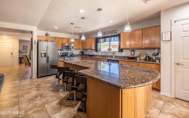 13570 E Hampden Green Way, Vail, AZ 85641 - kitchen featuring stainless steel appliances, brown cabinets, a kitchen island, a breakfast bar, and recessed lighting