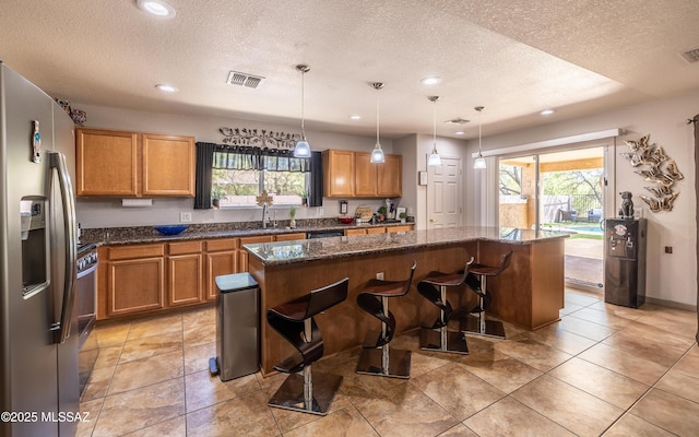 13570 E Hampden Green Way, Vail, AZ 85641 - kitchen featuring stainless steel refrigerator with ice dispenser, a textured ceiling, a kitchen island, healthy amount of natural light, and a sink
