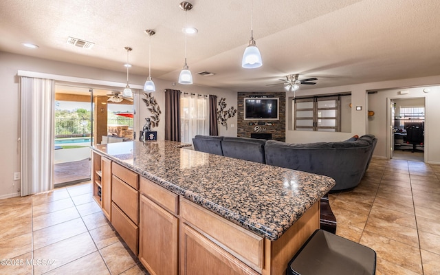 13570 E Hampden Green Way, Vail, AZ 85641 - kitchen featuring a ceiling fan, a textured ceiling, light tile patterned floors, a kitchen island, and baseboards
