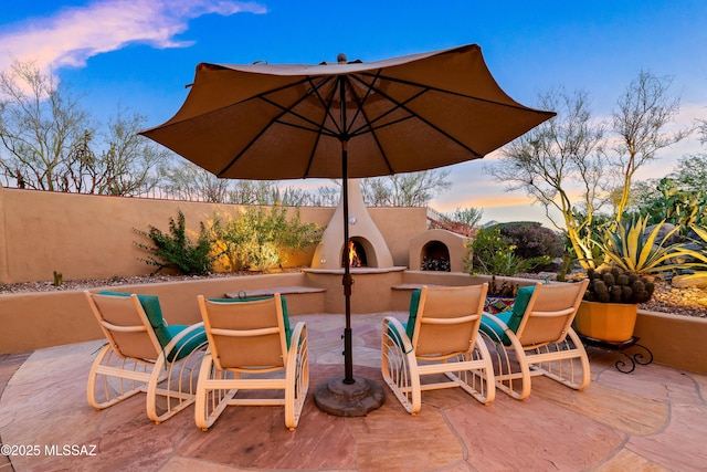 545 E Thunderstorm Pl, Oro Valley, AZ 85755 - patio terrace at dusk featuring exterior fireplace, a patio, and outdoor dining area