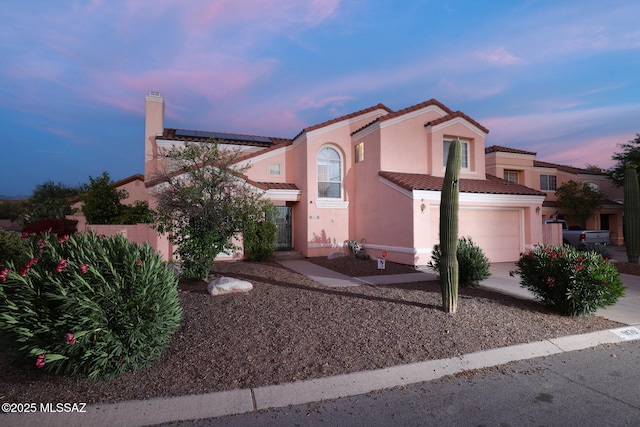 9870 N Meadow Flower Pl, Tucson, AZ 85742 - view of front of house featuring an attached garage, stucco siding, a tiled roof, and solar panels