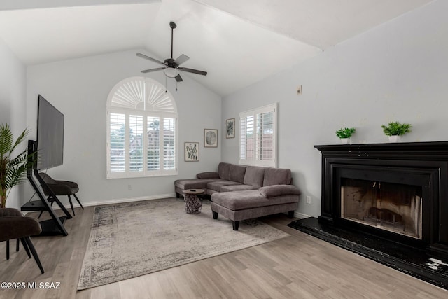 9870 N Meadow Flower Pl, Tucson, AZ 85742 - living room featuring ceiling fan, wood finished floors, vaulted ceiling, a fireplace with raised hearth, and baseboards