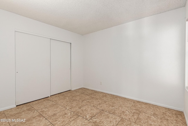 7244 S Camino Del Arco Iris, Tucson, AZ 85746 - unfurnished bedroom with a textured ceiling, a closet, light tile patterned floors, and baseboards