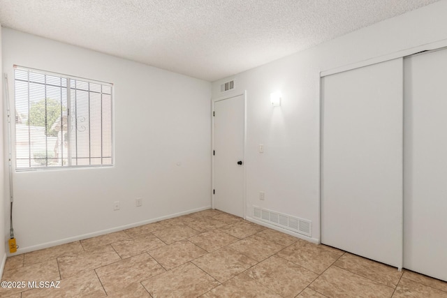 7244 S Camino Del Arco Iris, Tucson, AZ 85746 - unfurnished bedroom with a textured ceiling, a closet, light tile patterned flooring, and baseboards