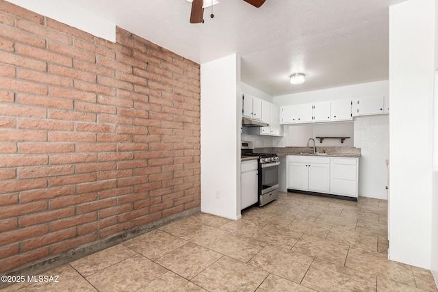 7244 S Camino Del Arco Iris, Tucson, AZ 85746 - kitchen with stainless steel gas stove, brick wall, ceiling fan, under cabinet range hood, and white cabinets