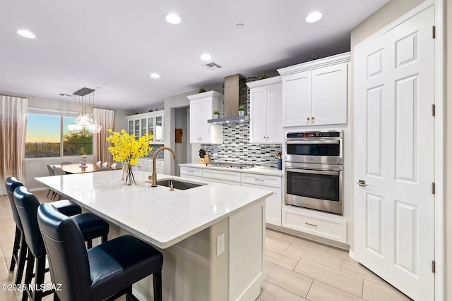7106 W Foothills Acacia Pl, Marana, AZ 85658 - kitchen featuring a sink, appliances with stainless steel finishes, wall chimney range hood, backsplash, and a center island with sink