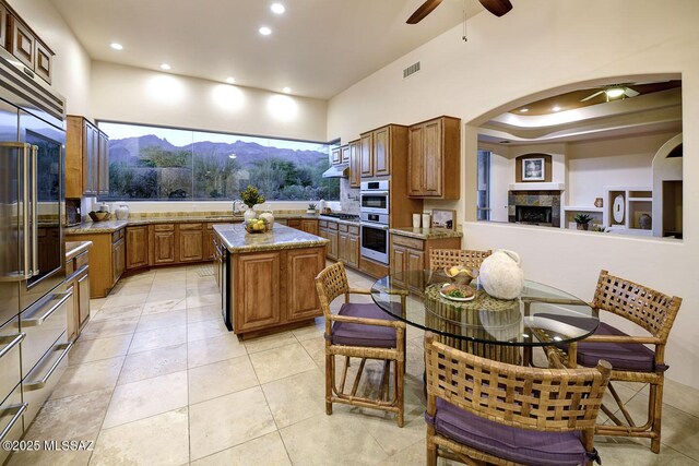 5269 N Pontatoc Rd, Tucson, AZ 85718 - kitchen featuring ceiling fan, built in refrigerator, a kitchen island, arched walkways, and brown cabinetry