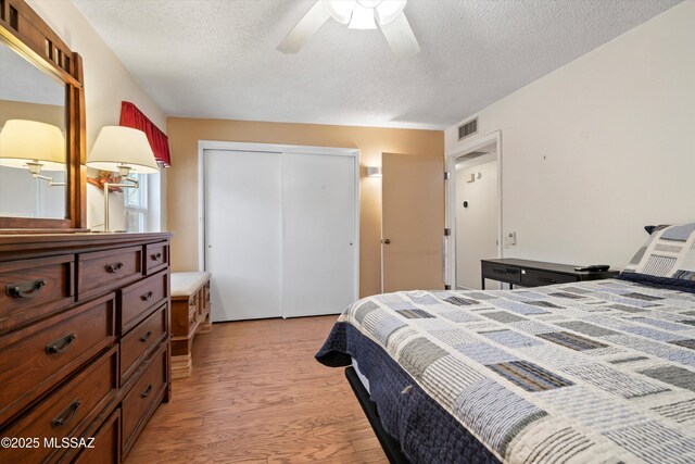 1018 Cll De La Temporada, Green Valley, AZ 85614 - bedroom with light wood-type flooring, a textured ceiling, a closet, and a ceiling fan