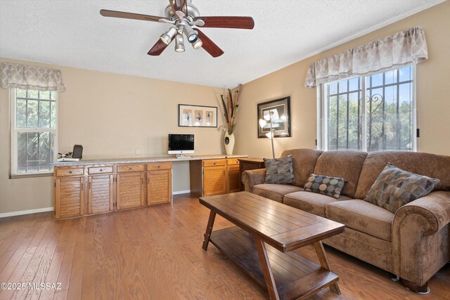 1018 Cll De La Temporada, Green Valley, AZ 85614 - living room with ceiling fan, light wood-style floors, a textured ceiling, baseboards, and a desk
