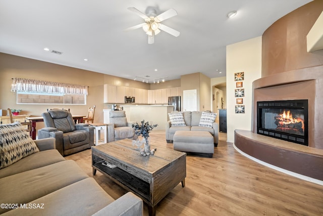 182 N Desert Park Pl, Tucson, AZ 85745 - living room with light wood-type flooring, a ceiling fan, a fireplace, and recessed lighting