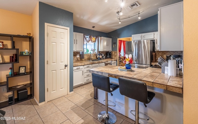 253 Grillo Ct, Rio Rico, AZ 85648 - kitchen featuring appliances with stainless steel finishes, backsplash, white cabinets, and vaulted ceiling