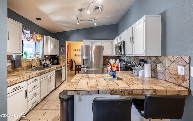 253 Grillo Ct, Rio Rico, AZ 85648 - kitchen featuring stainless steel appliances, a sink, a peninsula, tasteful backsplash, and white cabinets