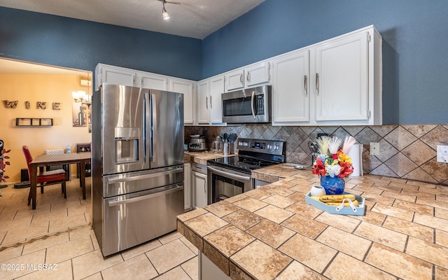 253 Grillo Ct, Rio Rico, AZ 85648 - kitchen featuring stainless steel appliances, white cabinetry, backsplash, and a peninsula