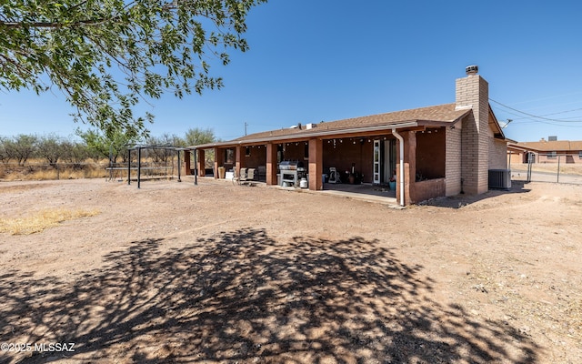 253 Grillo Ct, Rio Rico, AZ 85648 - rear view of house featuring central AC unit, a chimney, and a patio area