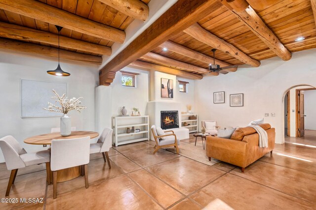3008 E Placita Santa Lucia, Tucson, AZ 85716 - living area featuring a wood ceiling with exposed beams, arched walkways, finished concrete flooring, a lit fireplace, and a ceiling fan