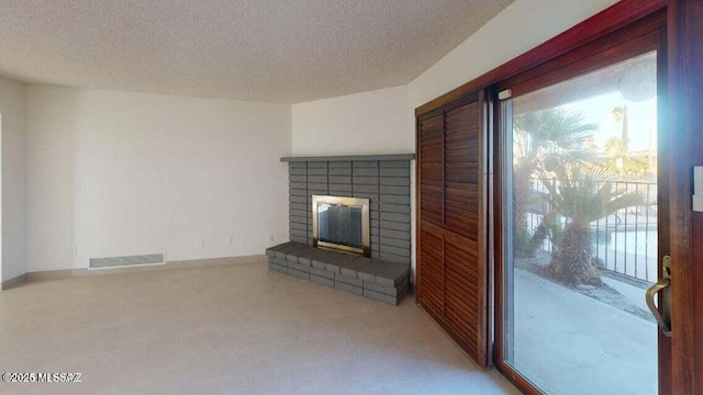 unfurnished living room featuring healthy amount of natural light, a fireplace, and a textured ceiling