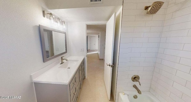 bathroom featuring vanity, bathtub / shower combination, and a textured wall