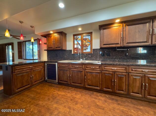 kitchen featuring beverage cooler, a peninsula, dark wood finished floors, tasteful backsplash, and recessed lighting