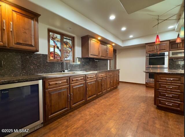 kitchen with stainless steel double oven, dark wood finished floors, backsplash, recessed lighting, and a sink