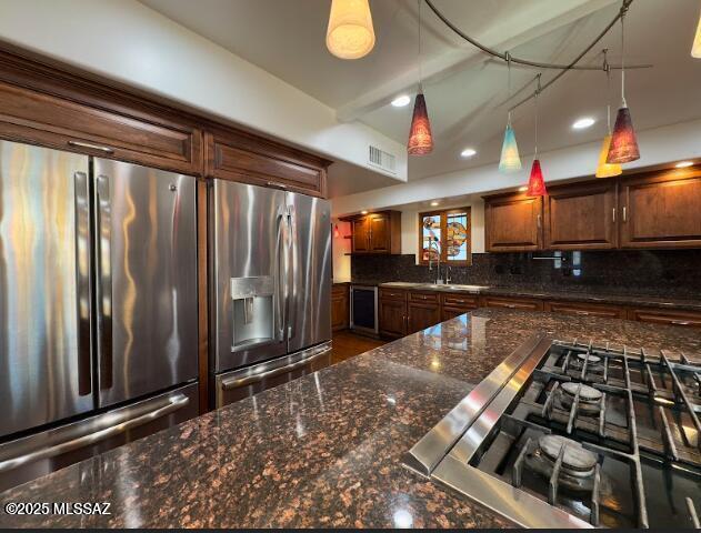 kitchen with stainless steel appliances, decorative backsplash, recessed lighting, hanging light fixtures, and dark stone counters