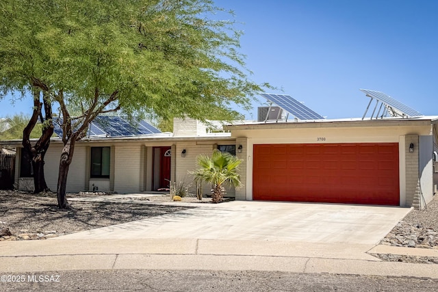 3700 S Serena Ln, Tucson, AZ 85730 - view of front of property with roof mounted solar panels, a garage, driveway, and brick siding