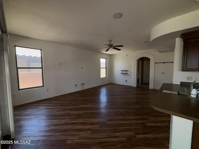 262 W Calle Paso Suave, Sahuarita, AZ 85629 - unfurnished living room with arched walkways, dark wood-style floors, and ceiling fan