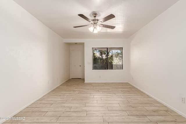 empty room featuring a ceiling fan, light wood finished floors, and baseboards