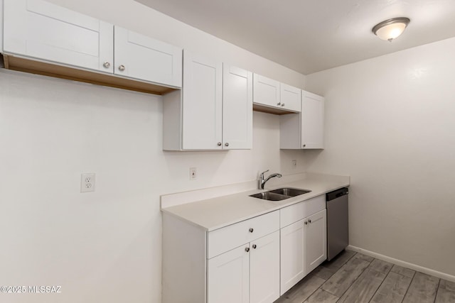 kitchen with a sink, dishwasher, light wood-style floors, white cabinetry, and light countertops